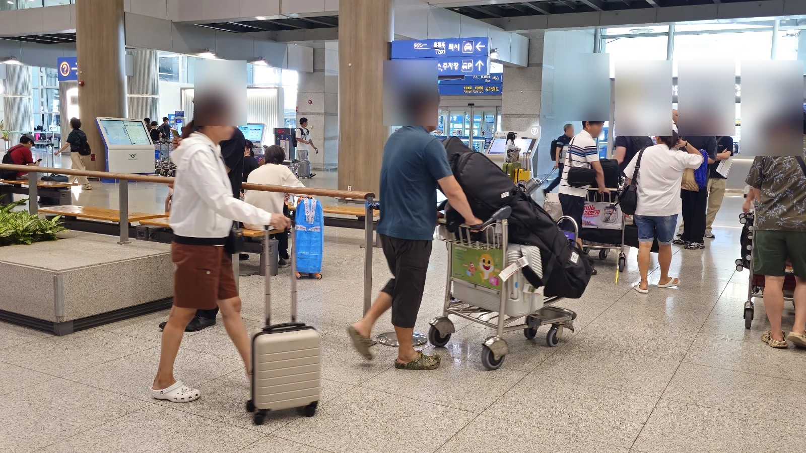 Passengers with luggage moving through an airport arrival hall in Korea
