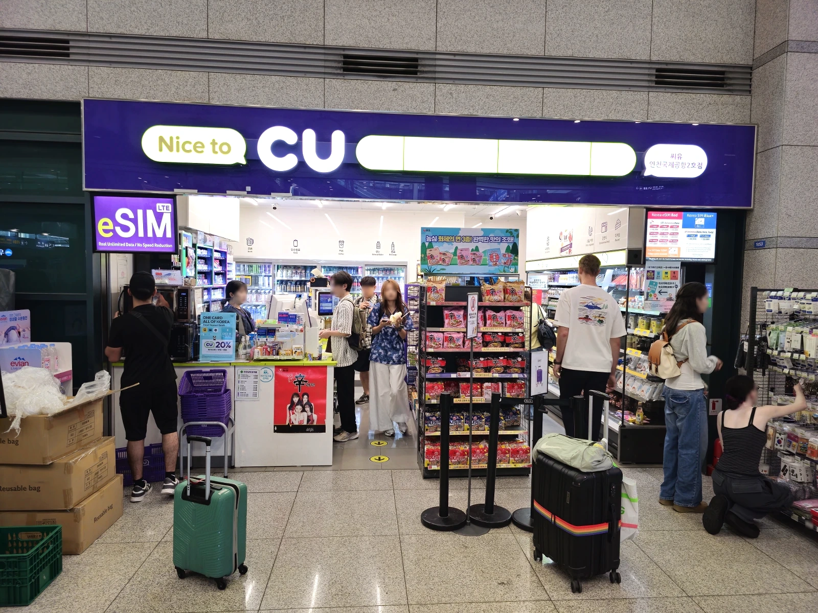 Travelers and luggage inside a CU convenience store at an airport